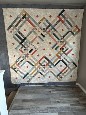 Bakers Dozen Quilt by Michele Urbany Neely Puluti, showing thirteen interlocking geometric blocks in cream, coral, navy, teal, gold, and patterned fabrics