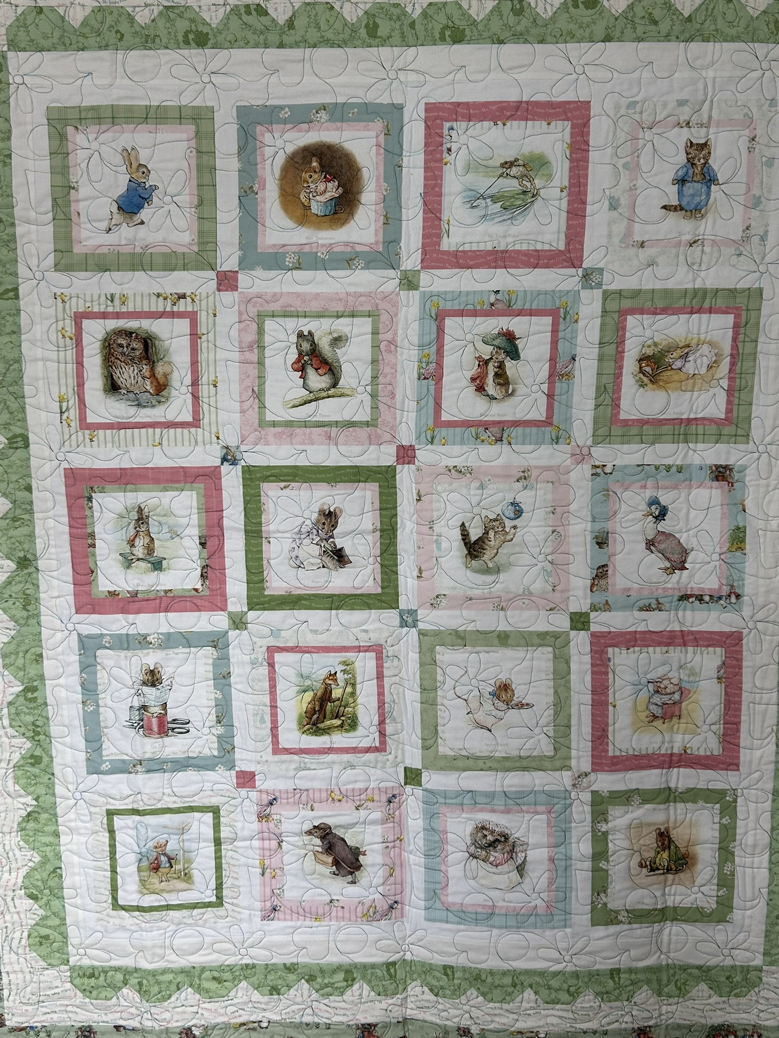 Full view of Michele Urbany Neely Puluti’s Beatrix Potter Peter Rabbit baby quilt with pastel character blocks and green border