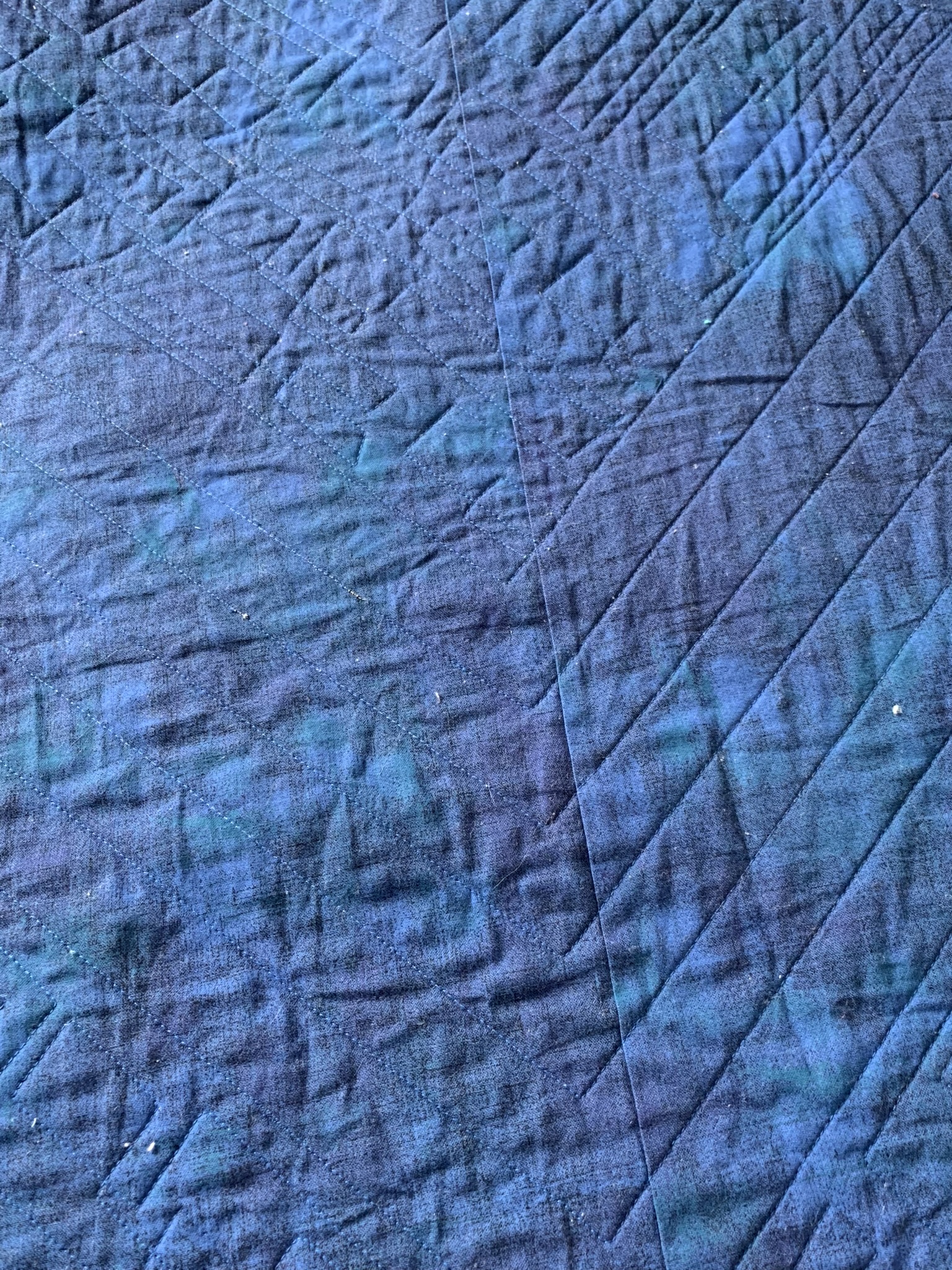 Close-up of blue geometric stitching on the reverse of Evan’s Quilt