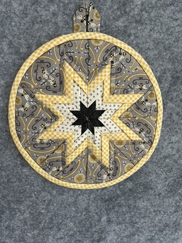 Round Scrappy Potholder with a black, white, gray, and yellow star pattern