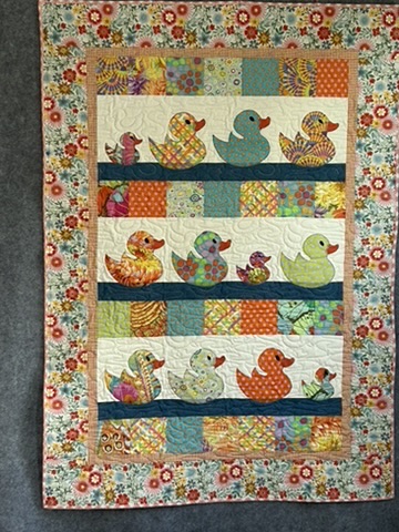 Quack Quack Frankie Baby Quilt by Michele Urbany Neely Puluti, featuring rows of colorful appliquéd ducks framed by floral fabric