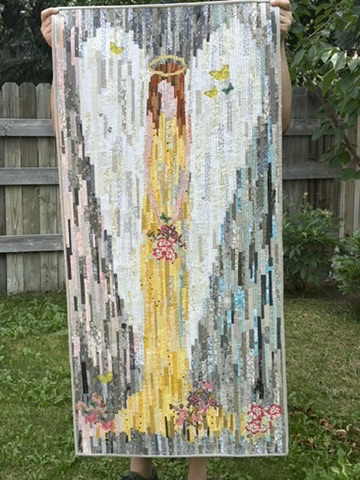 Angel wall hanging by Michele Urbany Neely Puluti, with a luminous golden figure, floral accents, butterflies, and vertical strip piecing