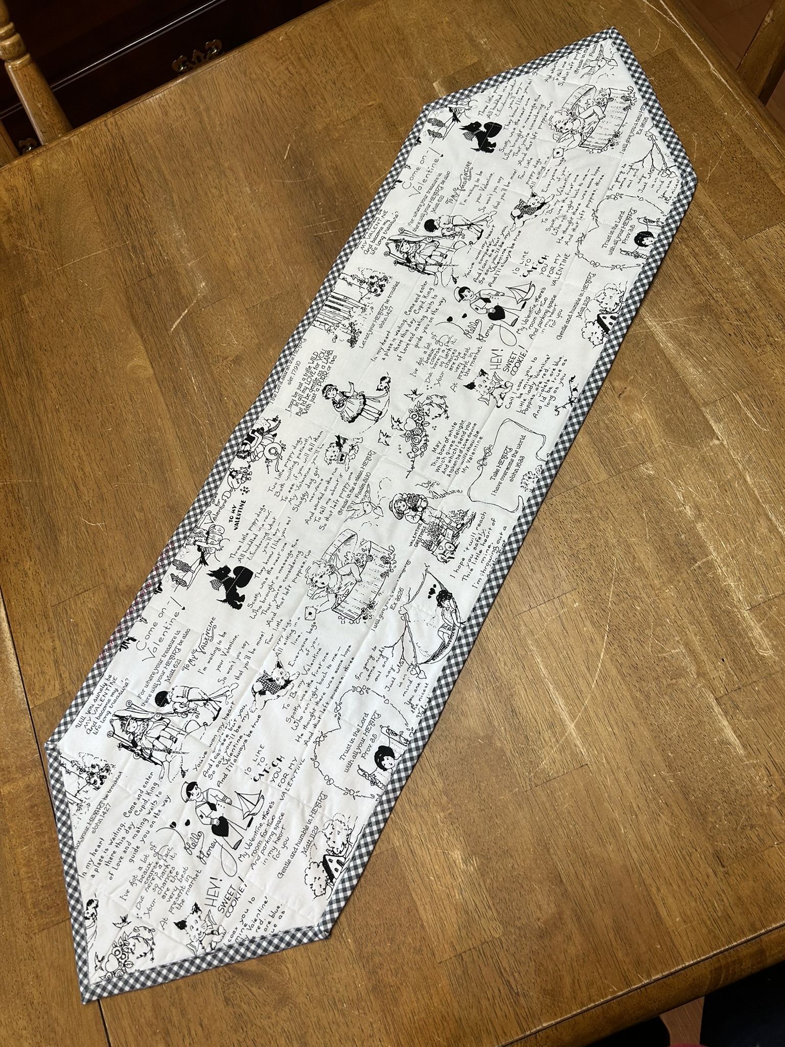 Reverse view of Barney’s Valentine’s Day Table Runner with black-and-white vintage Valentine illustrations and gingham binding