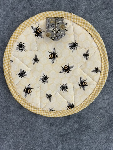 Reverse view of a Scrappy Potholder in a bee print with yellow gingham binding