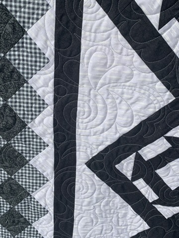Close-up of the curved stitching, black borders, and gingham patchwork in CHURN DASH