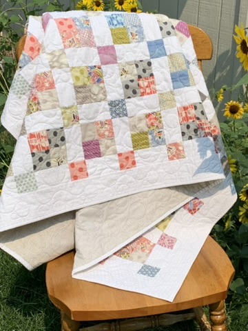 Folded Squares Quilt showing its colorful patchwork, scrolling quilting, border, and reverse