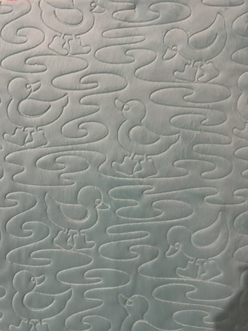 Close-up of duck-shaped quilting and flowing water-ripple stitching on the reverse of Quack Quack Frankie Baby Quilt