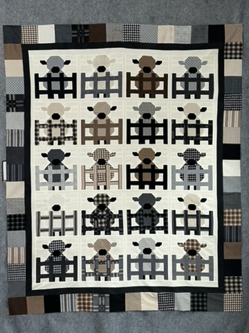 Unquilted sheep quilt top by Michele Urbany Neely Puluti with twenty patchwork sheep standing behind fences in black, gray, cream, brown, and checked fabrics