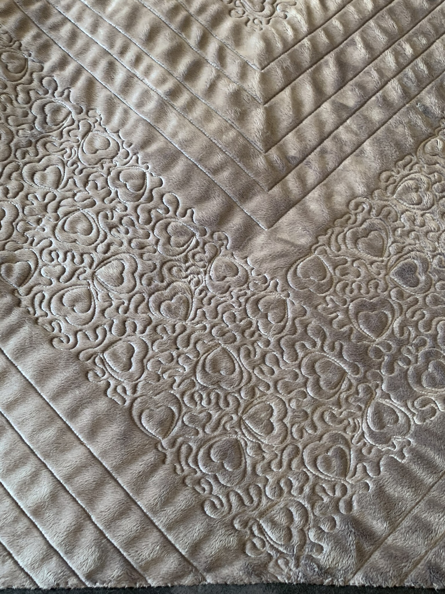 Close-up of the heart motifs and precise geometric stitching on the reverse of Emma’s Quilt
