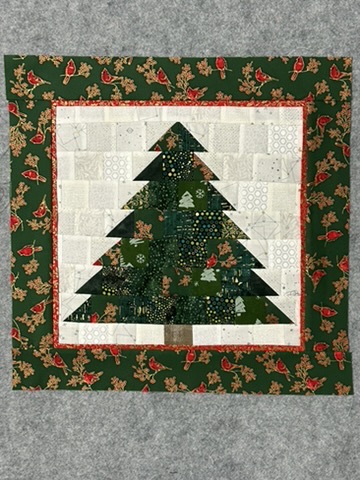 Green Christmas tree wall hanging by Michele Urbany Neely Puluti with a white patchwork background and holly-and-cardinal border
