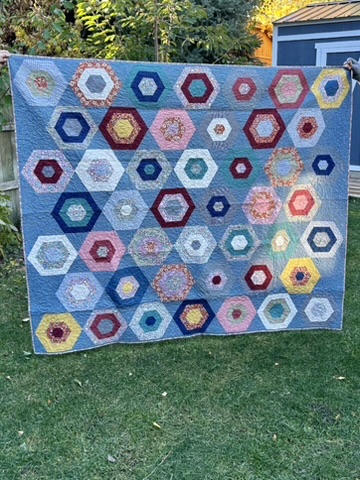 Front view of Anna’s Quilt by Michele Urbany Neely Puluti, featuring colorful nested hexagons on a blue field