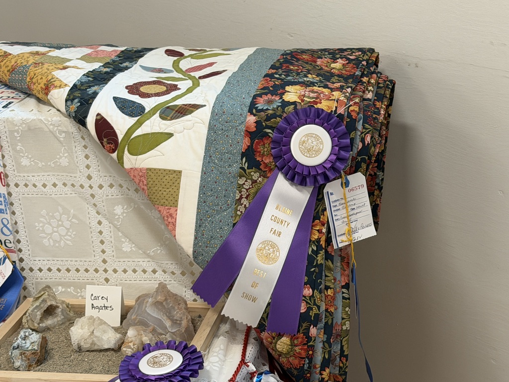 Best of Show ribbon resting on The Farmer’s Daughter quilt at the 2026 Blaine County Fair