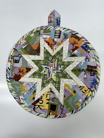 Round Scrappy Potholder with a green and cream star over a colorful New York novelty print