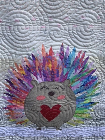 Close-up of the colorful hedgehog appliqué and spiral quilting on Hedgehog Baby Quilt
