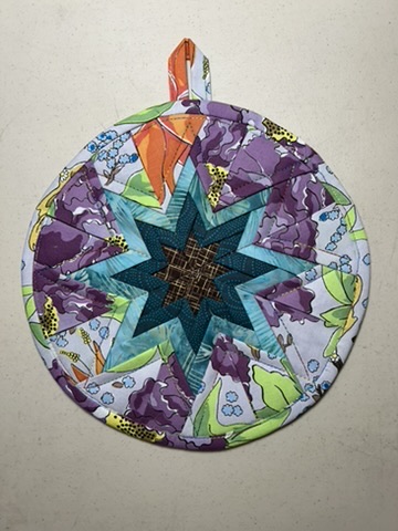 Round Scrappy Potholder with a teal and black star surrounded by purple floral fabric
