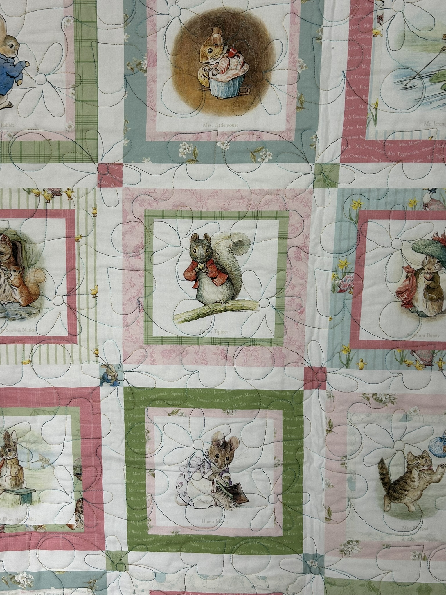 Close detail of framed Beatrix Potter characters and daisy quilting on the Peter Rabbit baby quilt
