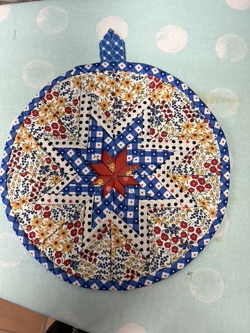 Round Scrappy Potholder with a red, blue, and cream star surrounded by tiny floral prints